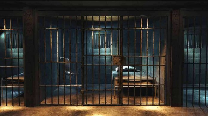 Prison cell with metal bars and a single bed