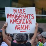Troubling Anti-Ice Note Written at ICE Shooting Site Teddy Williams at a protest holding a sign reading 'Make Immigrants American Again'