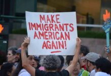 Troubling Anti-Ice Note Written at ICE Shooting Site Teddy Williams at a protest holding a sign reading 'Make Immigrants American Again'