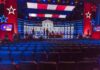 Lindsay Clancy’s Lawyer Begs Trump With Desperate Plea Debate stage with red and blue lighting and empty audience seats