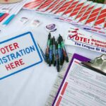 Mayor Openly Calls For NON-CITIZEN Votes in City Elections Voter registration table with forms, pens, and informational materials