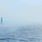 Green buoy in foggy sea