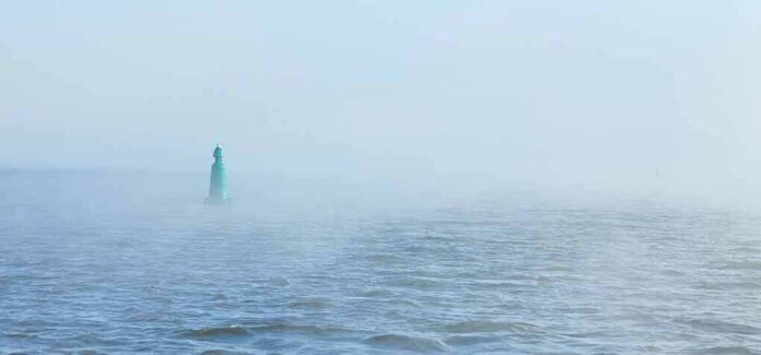 shutterstock_1870019050 Green buoy in foggy sea