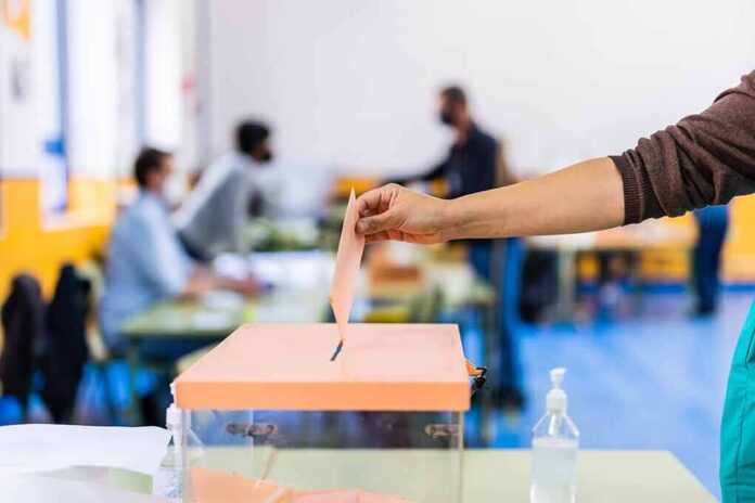 shutterstock_1967876806 Hand casting ballot into a box at a polling station