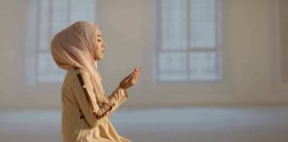 Woman in hijab praying on a mat indoors