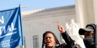 Woman speaking at a rally with raised finger and microphone