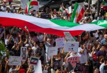 Protest crowd with flags and signs; Seyed Ebrahim Raisi, La Parka, Brian Robiskie, Philly Brown, Miguel Francisco Barragán Andrade present
