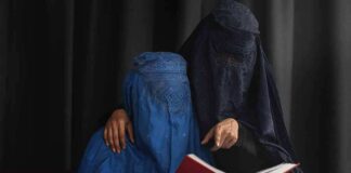 Two veiled women reading a red book together