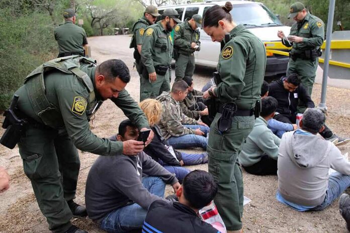 law enforcement officers process a seated group outdoors