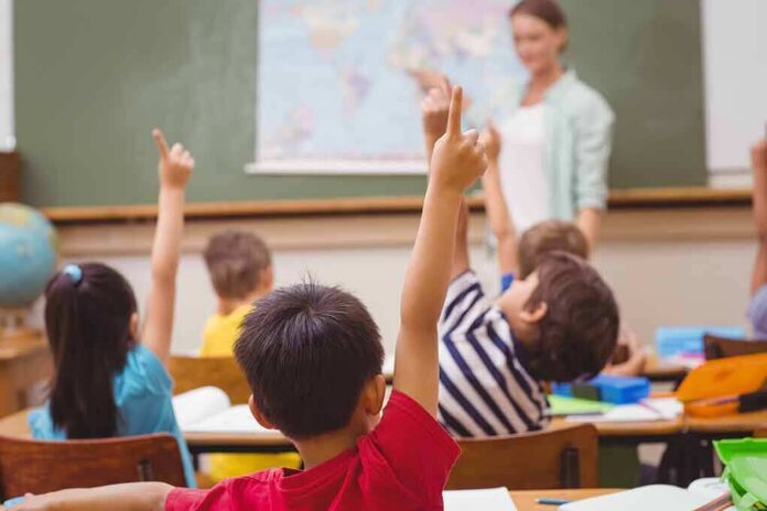 shutterstock_253351462 Students raising hands in a classroom