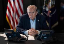 Trump Tells Rally-Goers To PAY High Gas Prices Person in suit seated at table with telephones