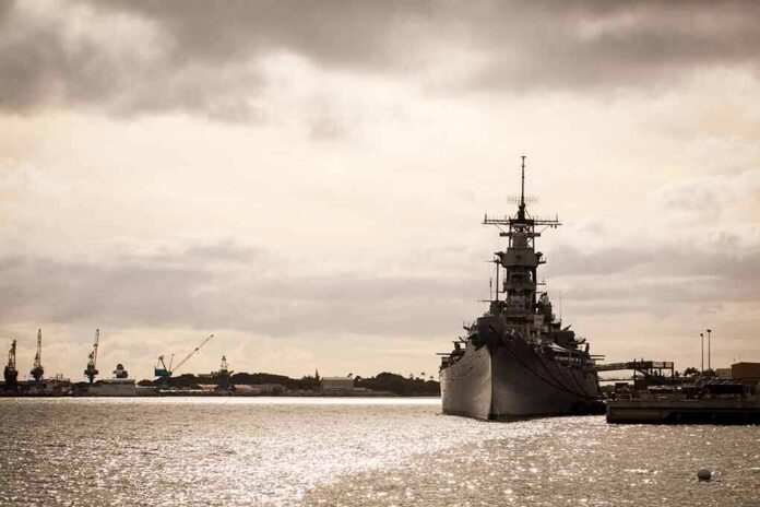 Battleship moored at a harbor under cloudy sky