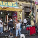 Food Truck Workers BOLT From ICE During Immigration Raid Street taco stand with people and a religious statue on a sidewalk