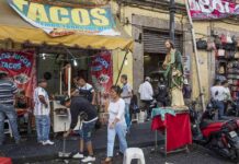 Food Truck Workers BOLT From ICE During Immigration Raid Street taco stand with people and a religious statue on a sidewalk