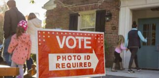 Red voting sign with arrow near people entering a polling place