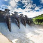 Hydroelectric dam spillway releasing water under bright sky