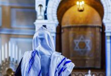 Person in white and blue prayer shawl facing ornate interior