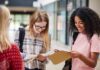 Country BANS Muslim Attire In Schools Students smiling while reading papers in a school hallway