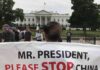 Protests Erupt in D.C As Trump Meets Xi Protester holding a large banner in front of the White House