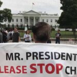 Protests Erupt in D.C As Trump Meets Xi Protester holding a large banner in front of the White House