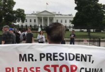 Protests Erupt in D.C As Trump Meets Xi Protester holding a large banner in front of the White House