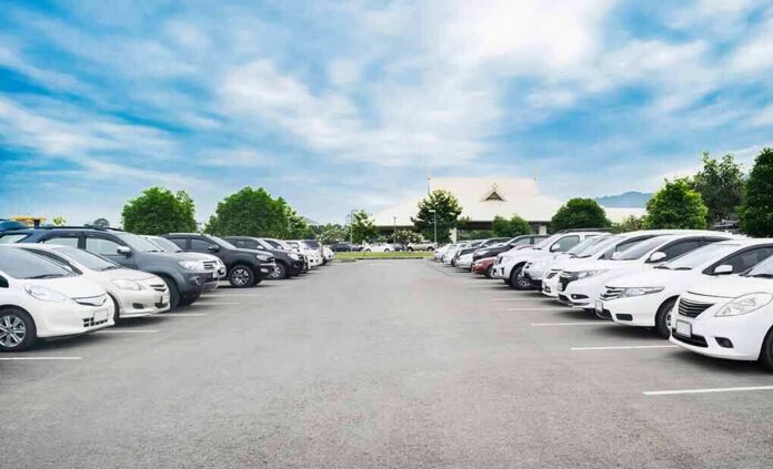 shutterstock_797260003 Parking lot lined with cars under a blue sky