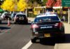 Police cars with flashing lights near school buses on a city street