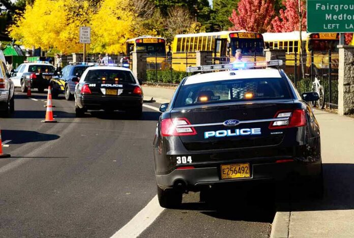 shutterstock_117302929 Police cars with flashing lights near school buses on a city street