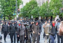 group of masked protesters walking through a city street
