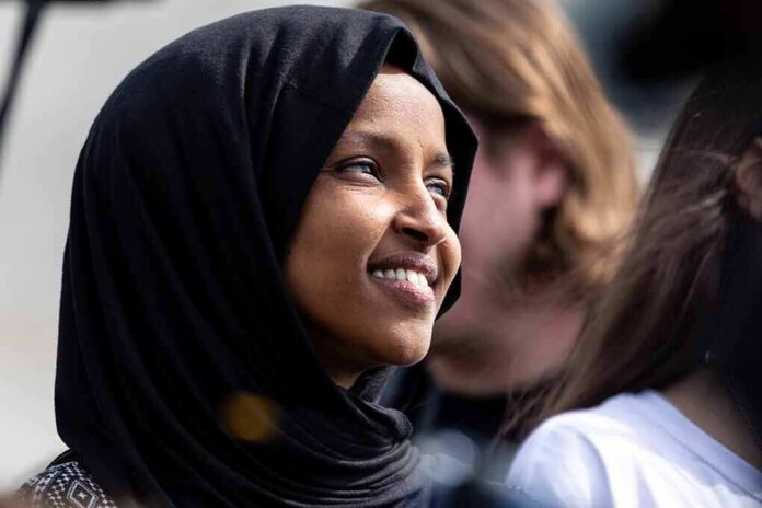 Ilhan Omar smiling in a black hijab at an outdoor event