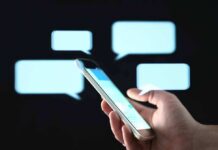 Hand holding smartphone with chat bubbles on dark background