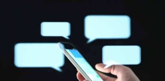 Hand holding smartphone with chat bubbles on dark background