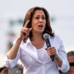 Kamala Harris speaking into a handheld microphone outdoors