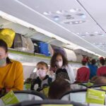 Passengers with masks boarding an airplane cabin