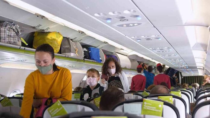 Passengers with masks boarding an airplane cabin