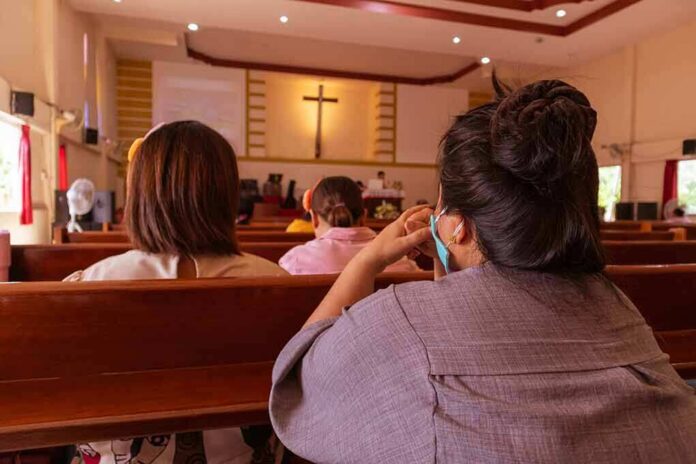 people seated in church pews facing a cross