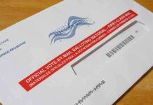 Trump Makes Emergency Voter Move in Blue State Mail-in ballot envelope with red label on wooden table