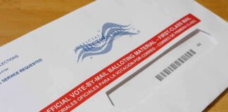 Mail-in ballot envelope with red label on wooden table