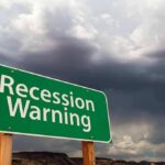 Debt Tsunami Hits Families – Worse Than GREAT RECESSION! Green roadside sign reading 'Recession Warning' under stormy sky