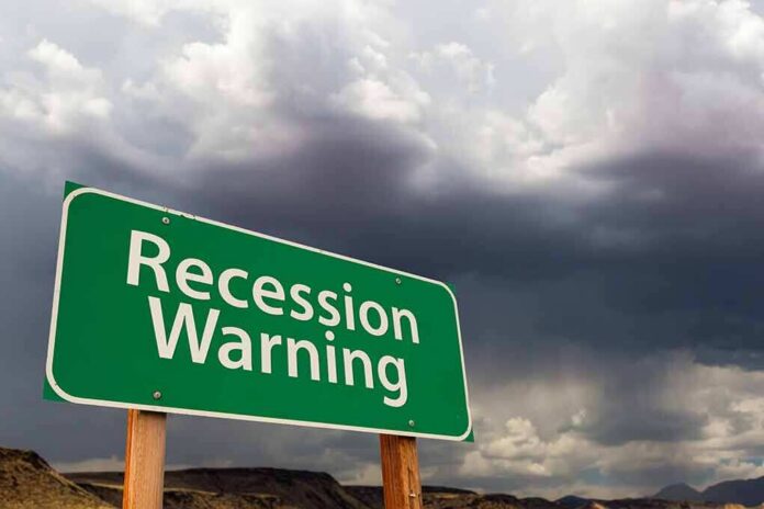 shutterstock_2152679709 Green roadside sign reading 'Recession Warning' under stormy sky