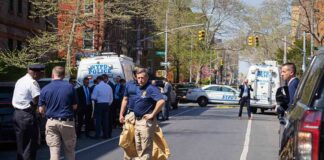 Police officers and investigators at a blocked city street scene