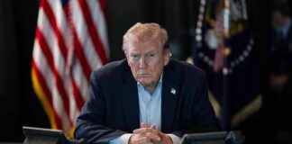 Donald Trump seated at a table between two desk phones