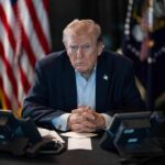 TRUMP Greenlights Firing Squad For Military Execution Donald Trump seated at a table between two desk phones
