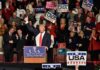 Donald Trump addresses a rally crowd at a podium, raising his fist