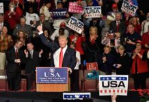 Donald Trump addresses a rally crowd at a podium, raising his fist
