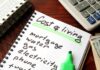 Budget notebook with cost of living list, calculator, and cash